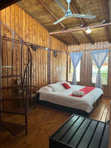 阿拉胡埃拉Hotel Pacande B&B的卧室配有一张床铺,位于带木墙的房间内