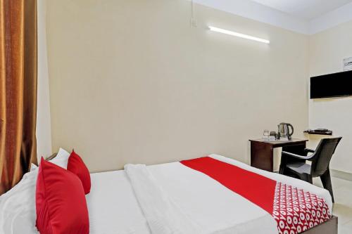 DispurOYO Flagship Lucky 7的一间卧室配有一张带红色枕头的床和一张书桌