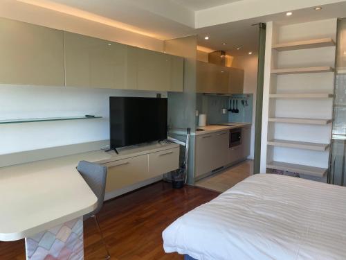 北京Beijing Elegant Seasons Park Apartment的一间卧室配有一张床和一台电视,还设有一间厨房