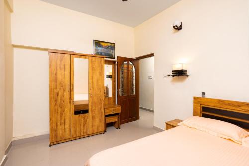 科钦Paradise Inn的一间卧室配有一张床和一个木制橱柜