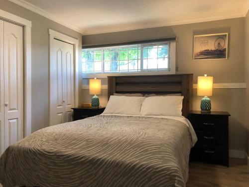 基洛纳Cheerful home close to downtown Kelowna的一间卧室配有一张带两盏灯的床和一扇窗户。