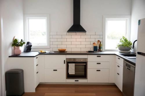 克莱斯韦克Enjoy a renovated retreat with outdoor bath的厨房配有白色橱柜和炉灶烤箱。