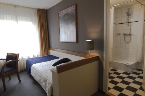 Den Dungen波尔古森斯酒店的一间卧室配有一张床,浴室设有淋浴。