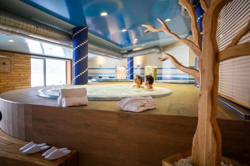 伏尔塔瓦河畔利普诺Amenity Hotel & Resort Lipno的两人在带树的按摩浴缸内
