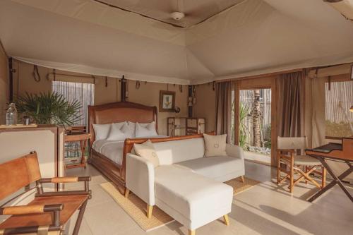 普吉镇Aladdin Luxury Camp Phuket的一间卧室配有一张床、一张沙发和一张桌子