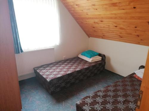 瓦沙罗什瑙梅尼Sarkifény Vendégház的小型客房设有两张床铺和木制天花板。