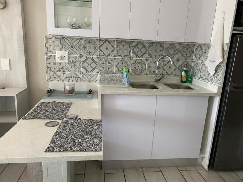 马盖特Uvongo Chalet 11的厨房配有白色橱柜和水槽