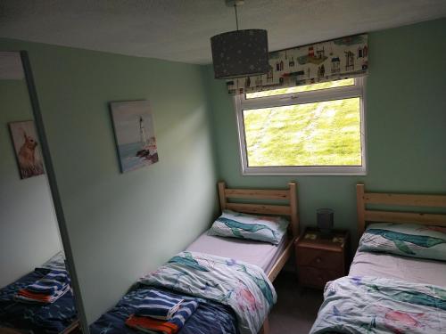 达特茅斯238 Norton Park, Dartmouth 2 bed holiday home with free parking的一间卧室设有两张床、镜子和窗户