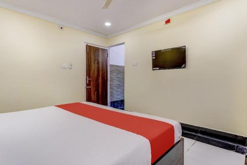 蒂鲁帕蒂Collection O Hotel Srinivasa Residency的卧室配有一张床,墙上配有电视。