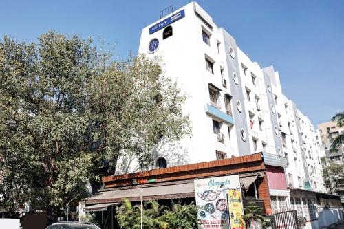 ChinchwadSuper Townhouse OAK Gharonda Residency Near Sant Tukaram Nagar Metro Station的一座高大的白色建筑,上面有钟楼