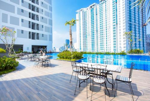 胡志明市Jessie Apartment - Infinity pool - Rivergate Residence的建筑前方设有带桌椅的庭院。