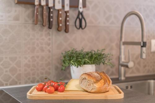 奥伯斯特多夫Landhaus Wiederkehr的厨房柜台上的一块带面包和西红柿的切板