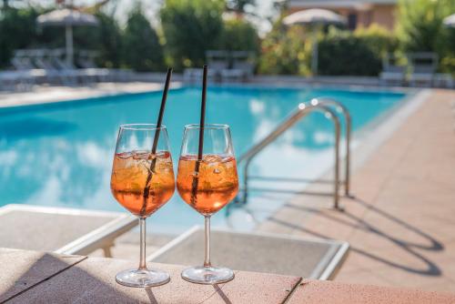 西尔米奥奈加德尼亚酒店的两杯酒坐在游泳池附近的桌子上
