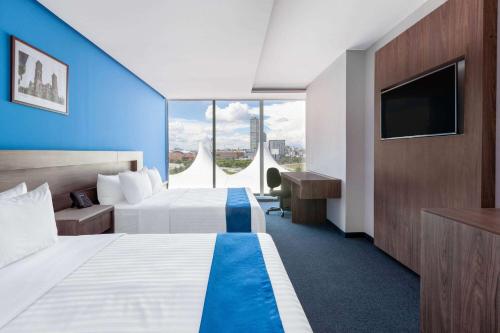 普埃布拉Wyndham Puebla Angelopolis的酒店客房设有两张床和一台平面电视。