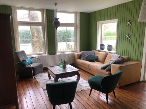米茨兰De Witte Handt的客厅拥有绿色的墙壁,配有沙发和椅子
