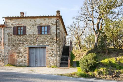 基安蒂盖奥勒Guest House il Gatto的一座古老的石头房子,设有车库和一棵树