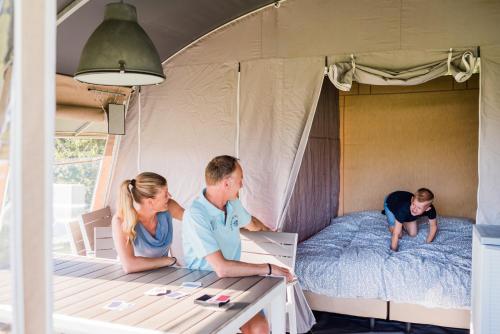 HerpelmontCountry Camp camping Domaine des Messires的一群人坐在帐篷里的床上