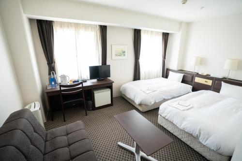神户Hotel Casabella Inn Kobe的酒店客房配有两张床和一张书桌