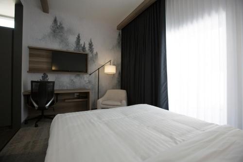 Saint-AmbroiseHotelia的一间卧室配有一张床、一台电视和一把椅子