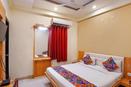 PrayagrajFabHotel Bliss Inn的一间卧室配有床和红色窗帘
