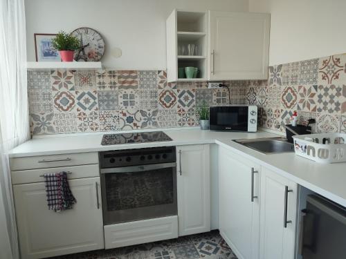 格德勒Palota Apartman的厨房配有白色橱柜和炉灶烤箱。