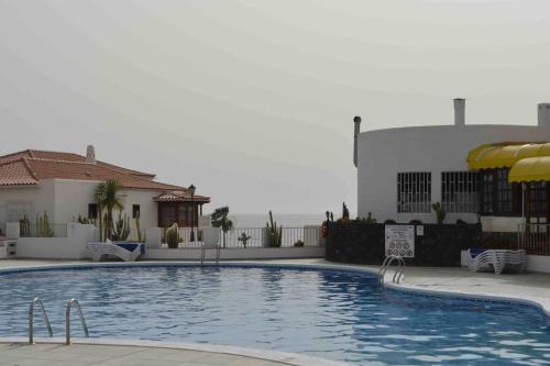 阿德耶Villa Tranquila, Playa del Duque的一座带遮阳伞的游泳池位于一座建筑旁边
