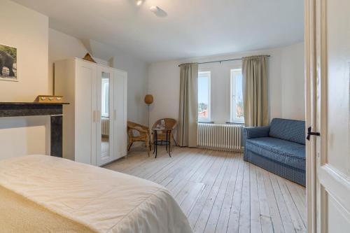 德哈恩Oceanide - Gerenoveerde luxe villa vlak bij het strand的一间卧室配有一张床和一张蓝色的沙发