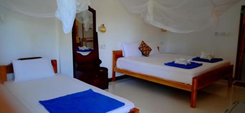 阿鲁甘湾SURF & SAND Hotel Arugambay的一间卧室配有两张带蓝白色床单的床