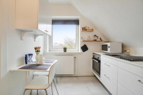 哥本哈根NICE TOPFLOOR STUDIO APARTMENT的白色的厨房,配有桌子和窗户