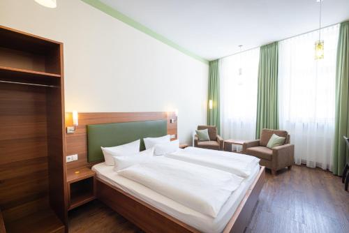 弗赖因斯海姆Altstadthof Freinsheim的卧室配有一张白色大床和两把椅子