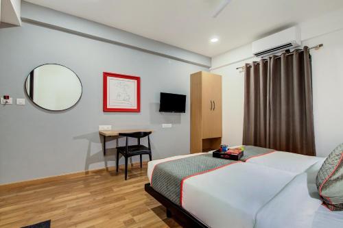 法里达巴德OYO Flagship Hotel Evergreen的一间卧室配有一张床、一张书桌和一面镜子
