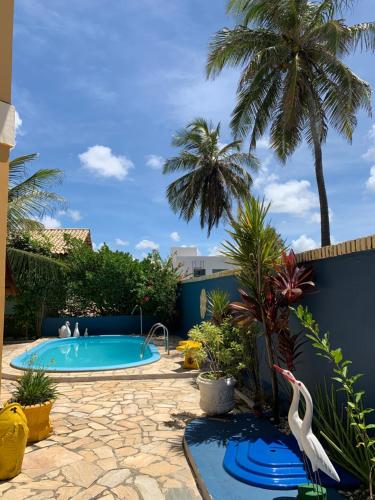 拉巴拉德纳圣米格尔Casa em condomínio, beira mar e piscina Barra de São Miguel - Maceió- AL的棕榈树后院的游泳池