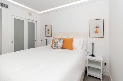 迈阿密海滩Stunning & Spacious Resort-Style Condo Across From Beach!的白色卧室配有带橙色枕头的大型白色床