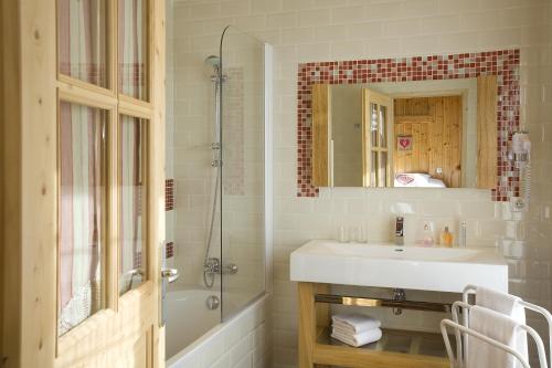 蒂涅Hôtel L'Arbina的一间带水槽、淋浴和镜子的浴室