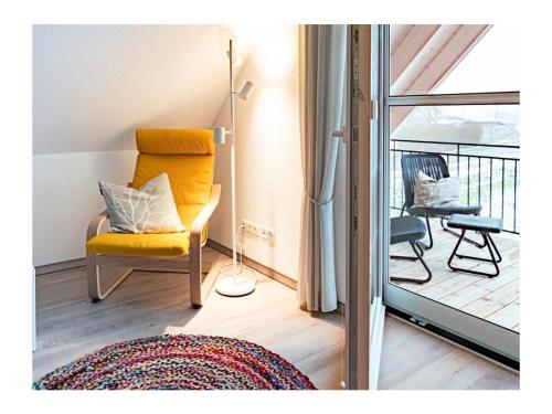 KrumminFerienhaus Familienkoje Hannah的一间带黄色椅子的客厅和一个阳台