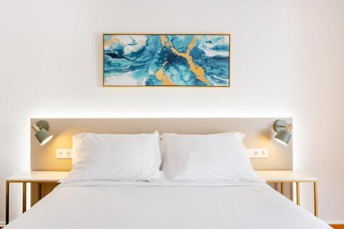 巴塞罗那Casa Lolita的卧室配有白色的床和墙上的绘画作品