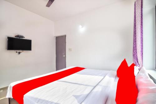 巴加Calangute Ocean Wave的一间配有电视的客房内的一张红色和白色的床