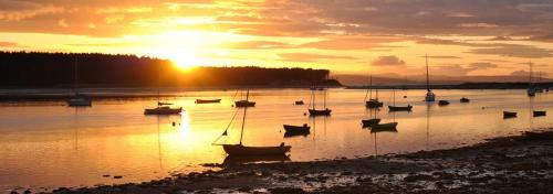 福里斯Driftwood Cottage, Findhorn Village的日落时分在水中的小船