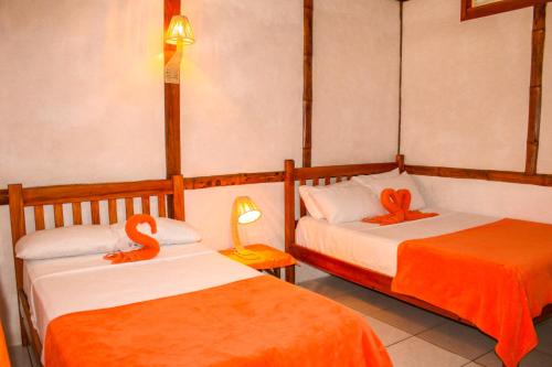 蒙塔尼塔HANGA ROA HOTEL的配有橙色床单的客房内的两张床