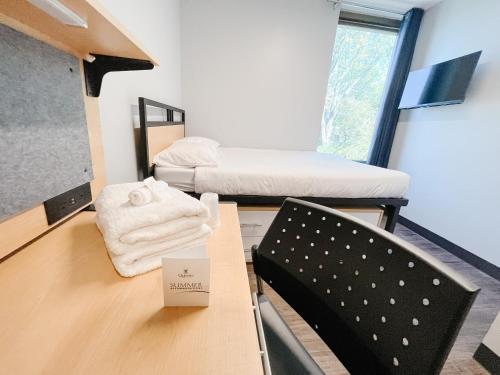 金斯顿Queen's University Residence的一间设有两张床、一张桌子和一把椅子的房间