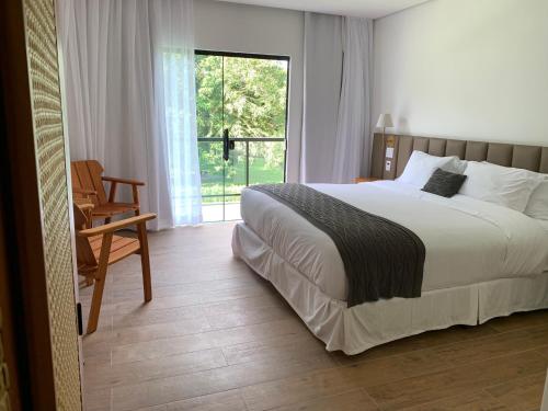 佩尼多Pousada Menino de Ouro的卧室配有床、椅子和窗户。