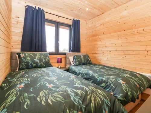 布里奇沃特The Lodge at Crossroads Farm的小木屋内一间卧室,配有两张床