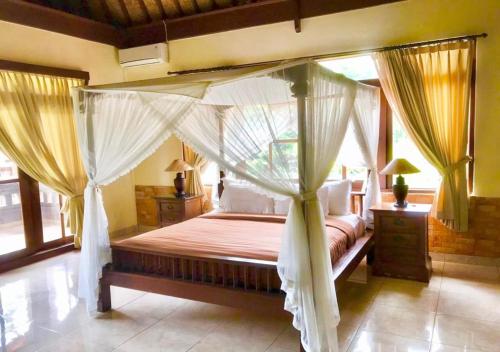 乌布潘德柏迈简易别墅酒店的一间卧室配有带窗帘的天蓬床