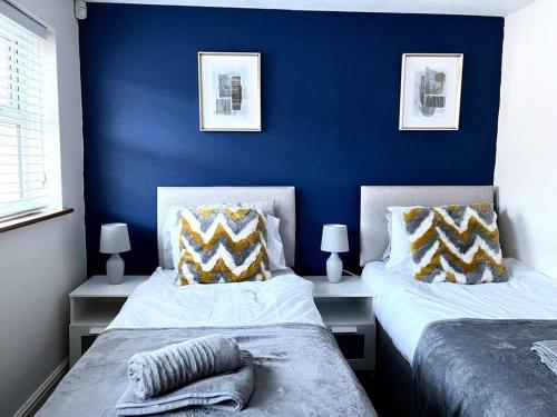 BuckinghamshireCentral Semi - Detached Home with Private Parking!的卧室设有两张床铺,拥有蓝色的墙壁