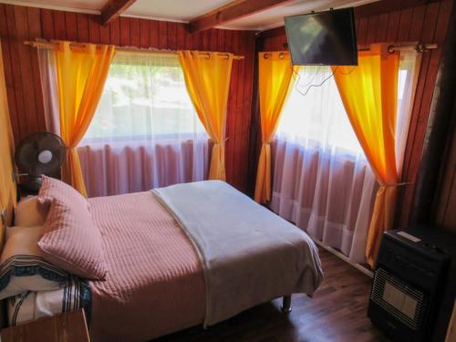 洛斯安赫莱斯CABAÑAS LOS CASTAÑOS的一间卧室配有床和两个带窗帘的窗户