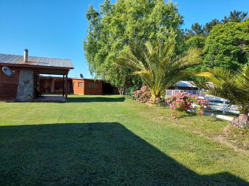 洛斯安赫莱斯CABAÑAS LOS CASTAÑOS的一座庭院,里面种着房子和棕榈树,种着草地