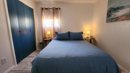 阿尔伯克基The Lilly Pad II的一间卧室配有一张带蓝色床单的床和两盏灯。