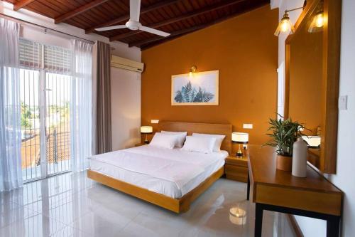 KaragampitiyaThe Greens Luxury Boutique Villa的一间卧室配有一张床、一张桌子和一个窗户。