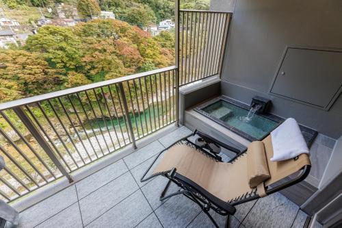 水上町Minakami Onsen Aratashi Minakami的阳台配有椅子和浴缸。