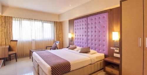 纳威孟买Hotel Corporate的一间卧室配有一张大床和一个紫色床头板